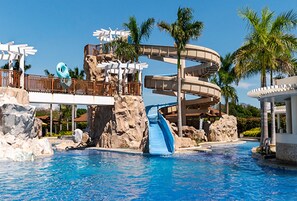 Un parc aquatique doté d’une grande piscine, d’un toboggan en spirale et de palmiers.
