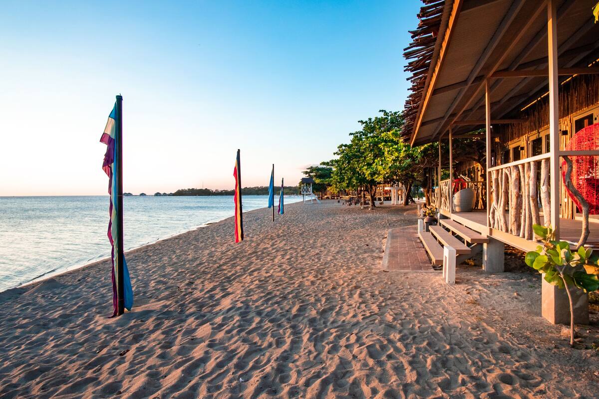 A beachside hotel with a wooden deck, benches, and a view of the sea.