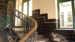 Una escalera con baldosas negras y ventanas con marcos verdes.