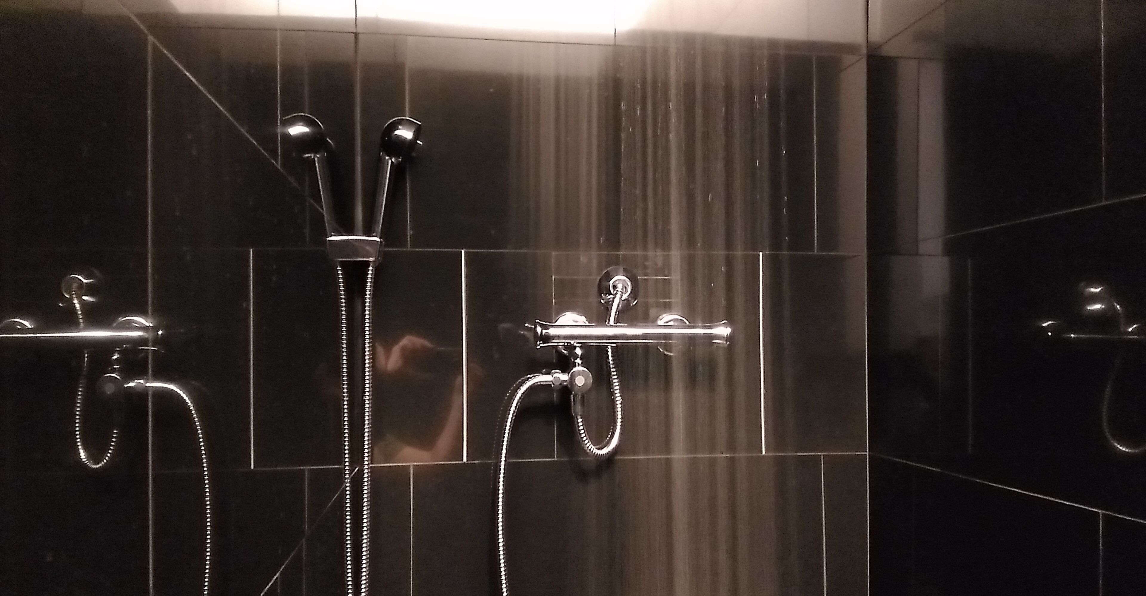 A shower area with chrome fixtures and a tiled wall.