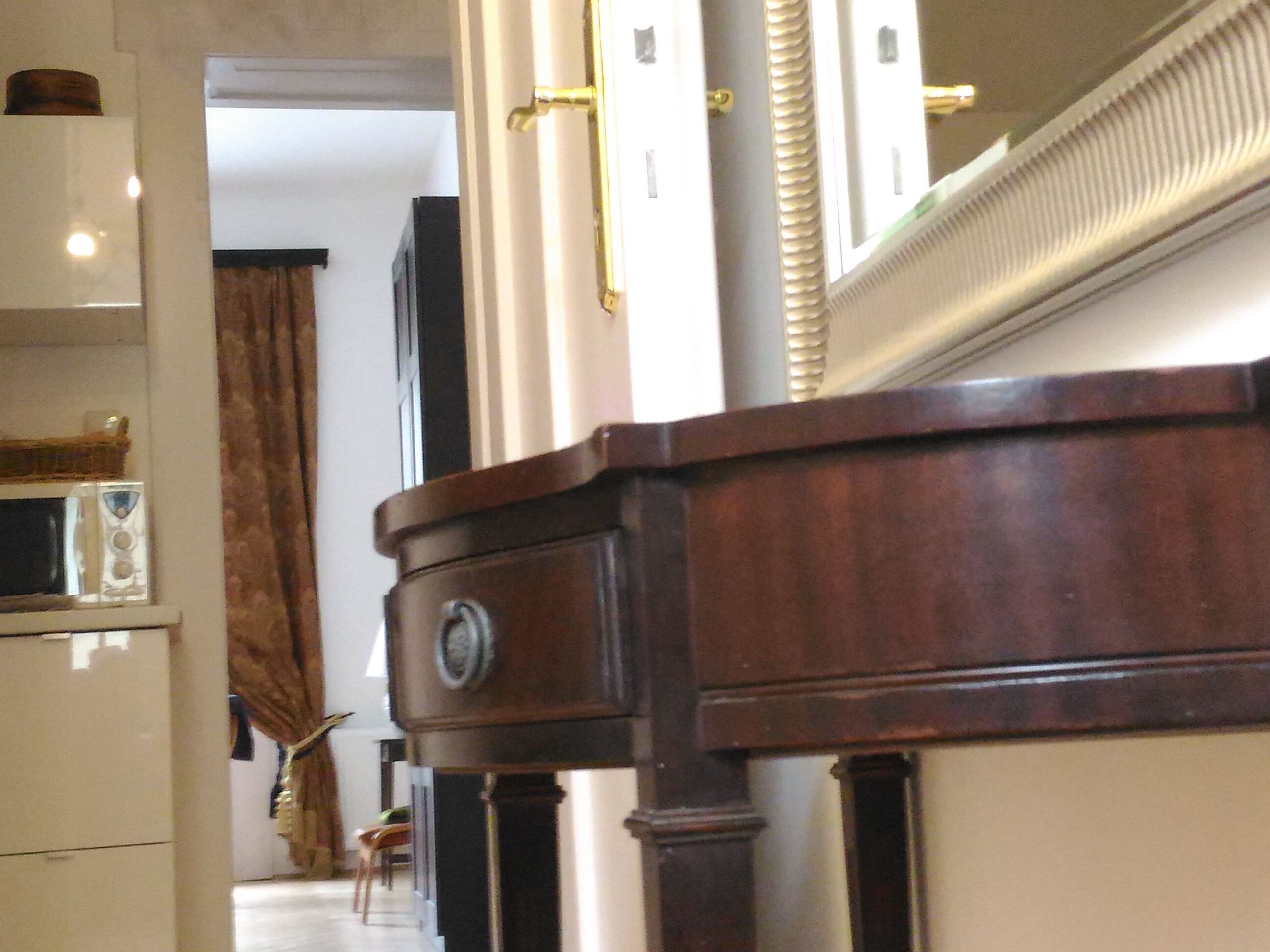 A hallway with a wooden door, a white cabinet, and a mirror.