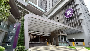 A modern hotel entrance with a covered walkway, a parking sign, and a large 'R' logo on the building. - Superb Room 500mMRT KLCC Pavillion Bukit Bintang (Kuala Lumpur)