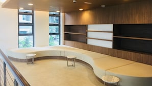 A modern waiting area with a curved bench, a small table, and built-in shelves. - Superb Room 500mMRT KLCC Pavillion Bukit Bintang (Kuala Lumpur)