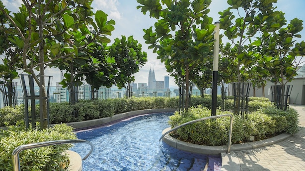 A swimming pool with a view of a city skyline, surrounded by trees and greenery. - Superb Room 500mMRT KLCC Pavillion Bukit Bintang (Kuala Lumpur)