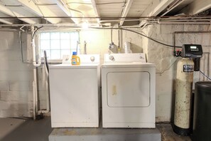 Ein Waschraum mit zwei weißen Waschmaschinen, einem Warmwasserbereiter und einer Gasflasche.