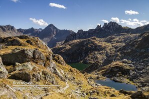 Paesaggio montuoso con terreno roccioso e un piccolo lago.