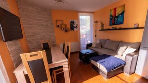 A modern living room with a wooden dining table, a sofa, and a TV mounted on the wall. - Family & Freelance Apartment in the center of Ski Amadé (Altenmarkt im Pongau)