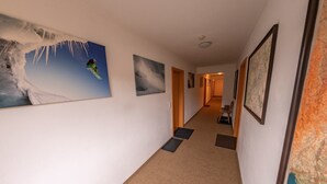 A hotel hallway with framed artwork on the walls, carpeted floors, and a wooden bench in the distance. - Family & Freelance Apartment in the center of Ski Amadé (Altenmarkt im Pongau)