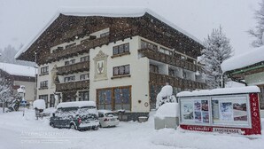 A multi-story building with a traditional Alpine architectural style, featuring a steeply pitched roof and a prominent entrance. - Family & Freelance Apartment in the center of Ski Amadé (Altenmarkt im Pongau)