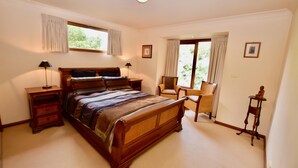 Un dormitorio con una cama grande, una silla, una mesita y una ventana con cortinas.