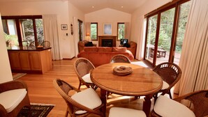 Un salón amplio con una mesa redonda de madera, sillas de mimbre, un sofá y una chimenea.