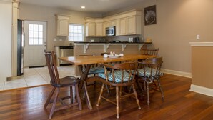 A spacious kitchen with wooden cabinetry, a central island, and a dining area with chairs. - Large + Comfortable! Great Location! Sleeps 9! (Philadelphia)