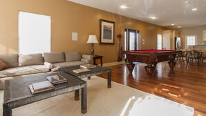 A spacious living room with a pool table, a sofa, and a dining area. - Large + Comfortable! Great Location! Sleeps 9! (Philadelphia)