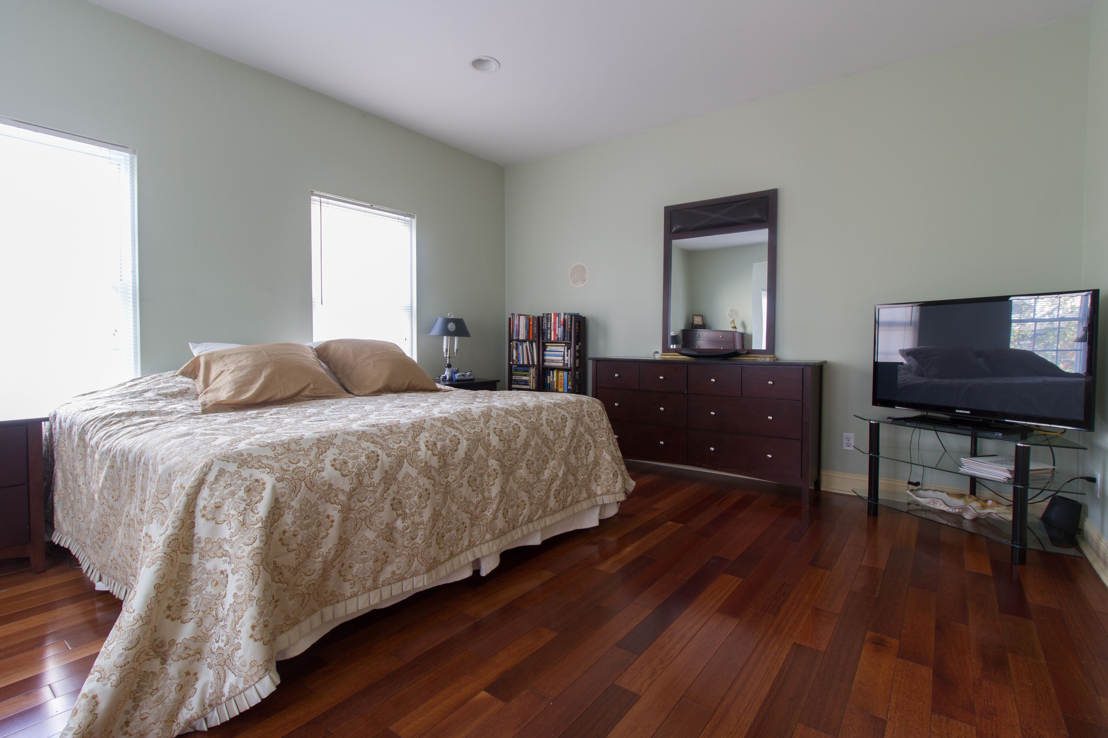 A bedroom with a bed, a dresser, a television, and a bookshelf.