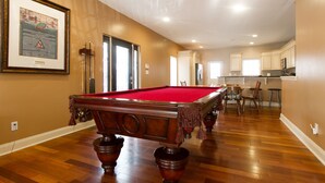 A spacious room with a pool table, wooden flooring, and a kitchen area in the background. - Large + Comfortable! Great Location! Sleeps 9! (Philadelphia)