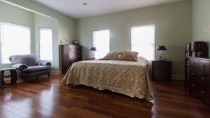A spacious bedroom with a large bed, a chair, a dresser, and a nightstand. - Large + Comfortable! Great Location! Sleeps 9! (Philadelphia)