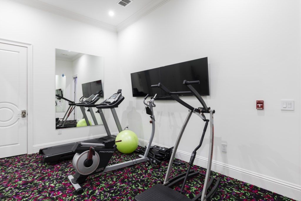 Un gimnasio con cintas de correr, elíptica y bicicleta estática.