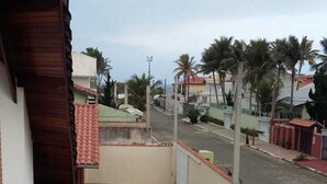 Un balcón con vista a una calle residencial, con casas y palmeras.