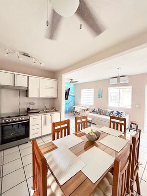 Een moderne keuken met witte kasten, een fornuis en een eethoek met een tafel en stoelen.