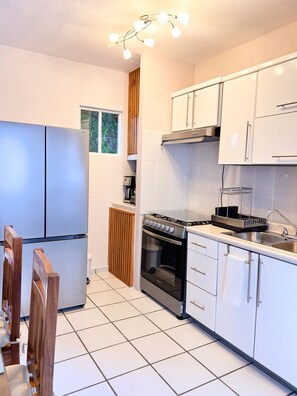 A modern kitchen with stainless steel appliances, white cabinetry, and a tiled floor. - Loft Yexalem - 2 Bedrooms in Puerto Morelos, 7 Min to the Beach (Puerto Morelos)