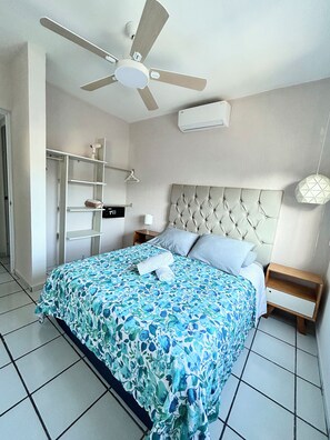 Een slaapkamer met een bed, een plafondventilator, een nachtkastje, een bedlamp en een kledingkast.