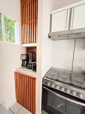 A compact kitchen with a gas stove, a coffee maker, and a toaster.