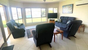 A living room with a ceiling fan, a flat-screen TV, and a large window. - 'The Shack' Copper Cove Marina - Only Steps to North Beach (Wallaroo)