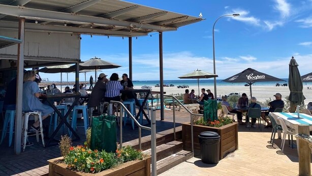 An outdoor seating area with tables and chairs, a covered walkway, and a view of the beach. - 'The Shack' Copper Cove Marina - Only Steps to North Beach (Wallaroo)