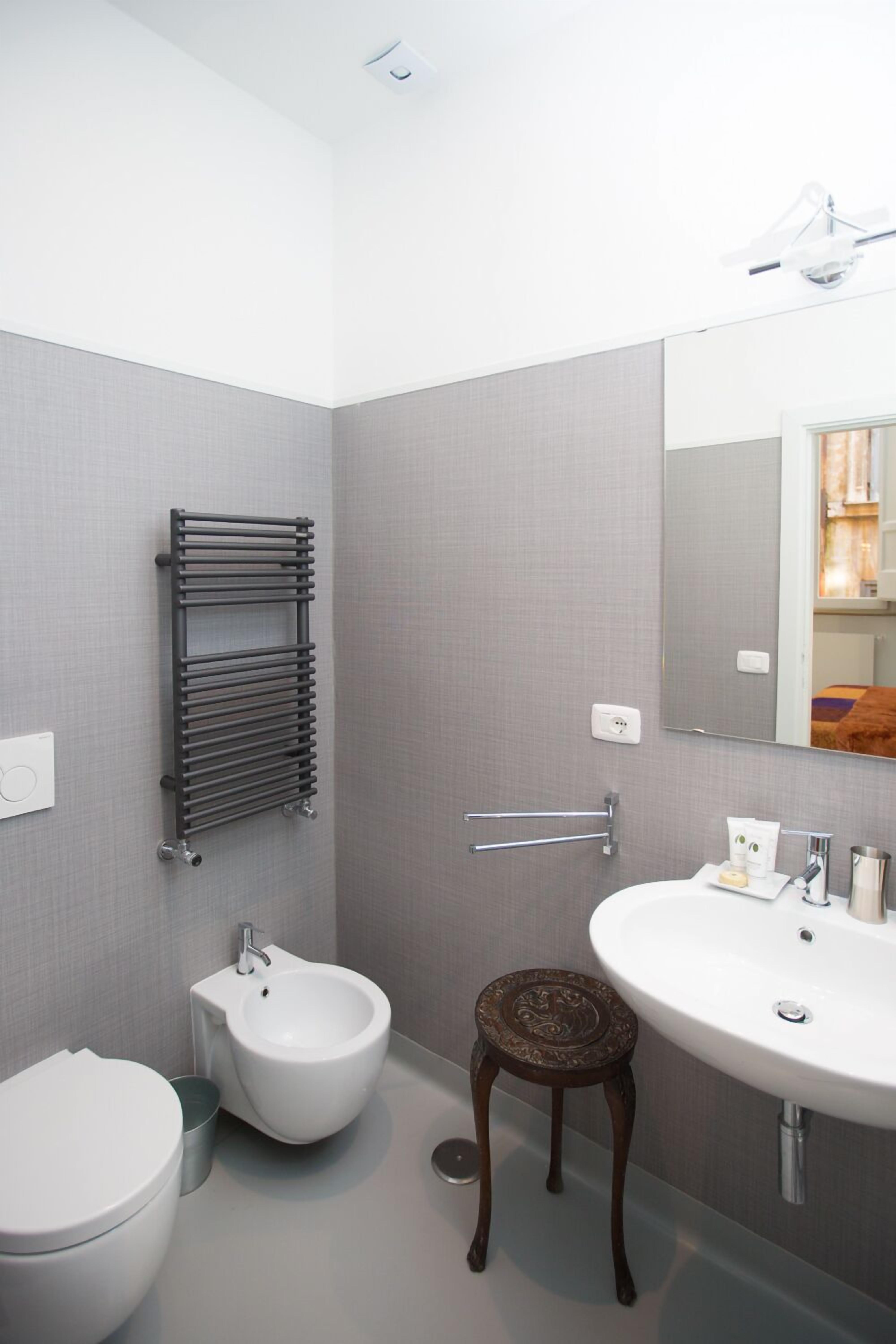 A modern bathroom with a bidet, a sink, a mirror, and a towel rack.