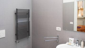 A modern bathroom with a bidet, a sink, a mirror, and a towel rack.