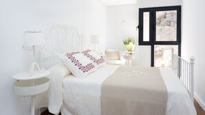 A bedroom with a bed, bedside table, lamp, chair, and a window with a view. - Luxury villa with panoramic ocean view (Guía de Isora)