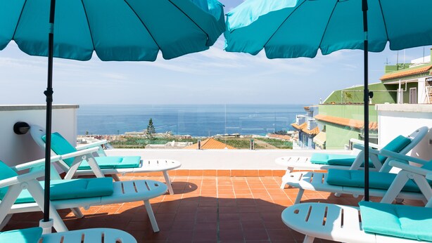 A terrace with white lounge chairs and turquoise cushions, overlooking a coastal view. - Luxury villa with panoramic ocean view (Guía de Isora)