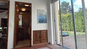 Une pièce avec une planche de surf, des meubles en bois, une œuvre d’art encadrée et une porte-fenêtre coulissante donnant sur un espace extérieur.