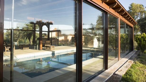 A modern pool area with glass walls and a wooden pergola. - Casa de Campo el Encinar - Paddleball, Pickleball, Swimming Pool and Barbecue (Santa Cruz del Retamar)