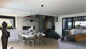 A modern kitchen with a dining area, a grey sofa with yellow cushions, and a statue of a Buddha. - Architect Villa with heated pool  (Séné)
