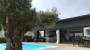 A modern house with a swimming pool, outdoor furniture, and a large tree. - Architect Villa with heated pool  (Séné)