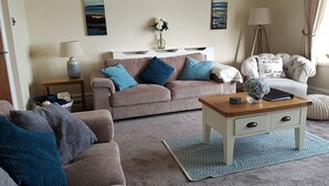 Un salon avec un canapé beige, une table basse en bois et un tapis à motifs.