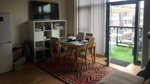 Un espace de vie compact comprenant une table à manger, des chaises, un téléviseur et une bibliothèque.