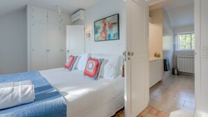Un dormitorio con cama, armario blanco y un cuadro en la pared.