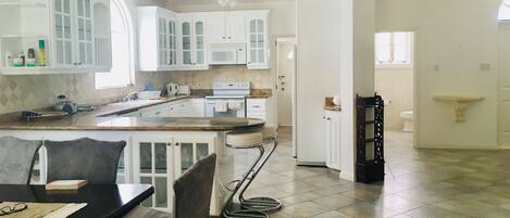 A spacious kitchen with white cabinetry, a central island, and a dining area with a table and chairs.