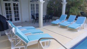 A poolside area with lounge chairs and a covered patio. - Beautiful spacious holiday home private shared pool with neighbour nr Sandy Lane (St James)