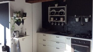 A modern kitchen with white cabinets, a black countertop, and a wooden ceiling.