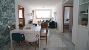 Ein moderner Wohnraum mit Essbereich, einer Couch und einer Küche im Hintergrund.