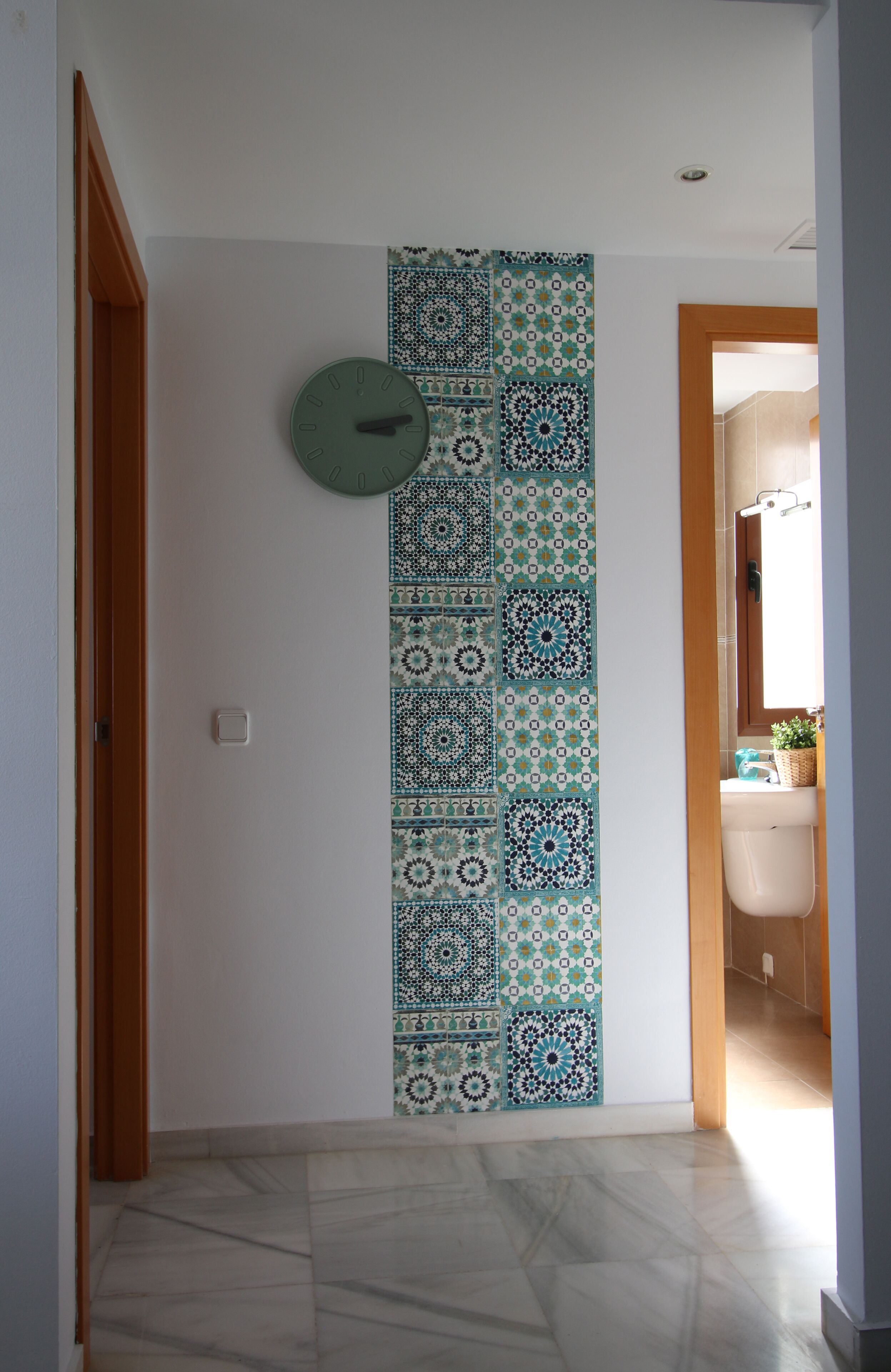 A hallway with a patterned wall and a clock.
