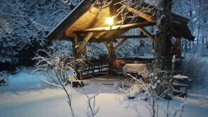 Una cabaña de madera con un porche cubierto, rodeada de árboles cubiertos de nieve.