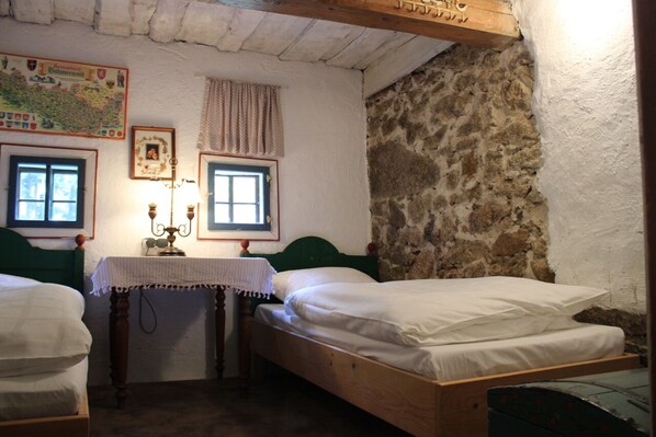 Een kamer met twee houten bedden, een kaart aan de muur en een klein tafeltje met een lamp.