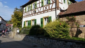 Un bâtiment traditionnel à colombages, doté d’un mur en pierre et d’un petit jardin à l’avant.
