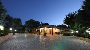 A courtyard with a building, stone flooring, and surrounding greenery.