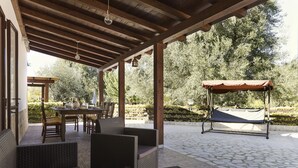 An outdoor patio with wicker furniture, a swing, and a table set for dining.