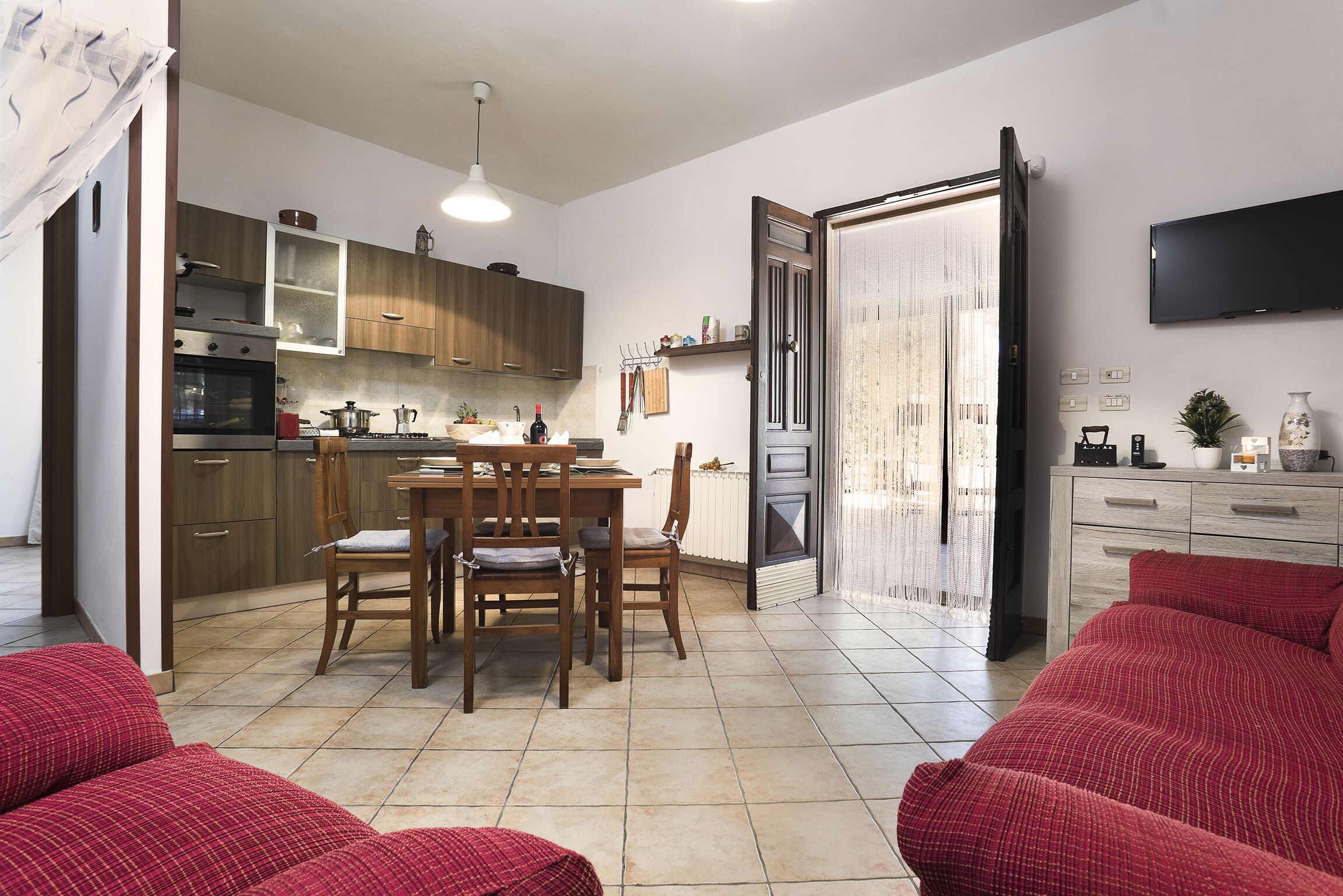 Une cuisine moderne avec des meubles en bois, une table à manger avec des chaises et un téléviseur fixé au mur.